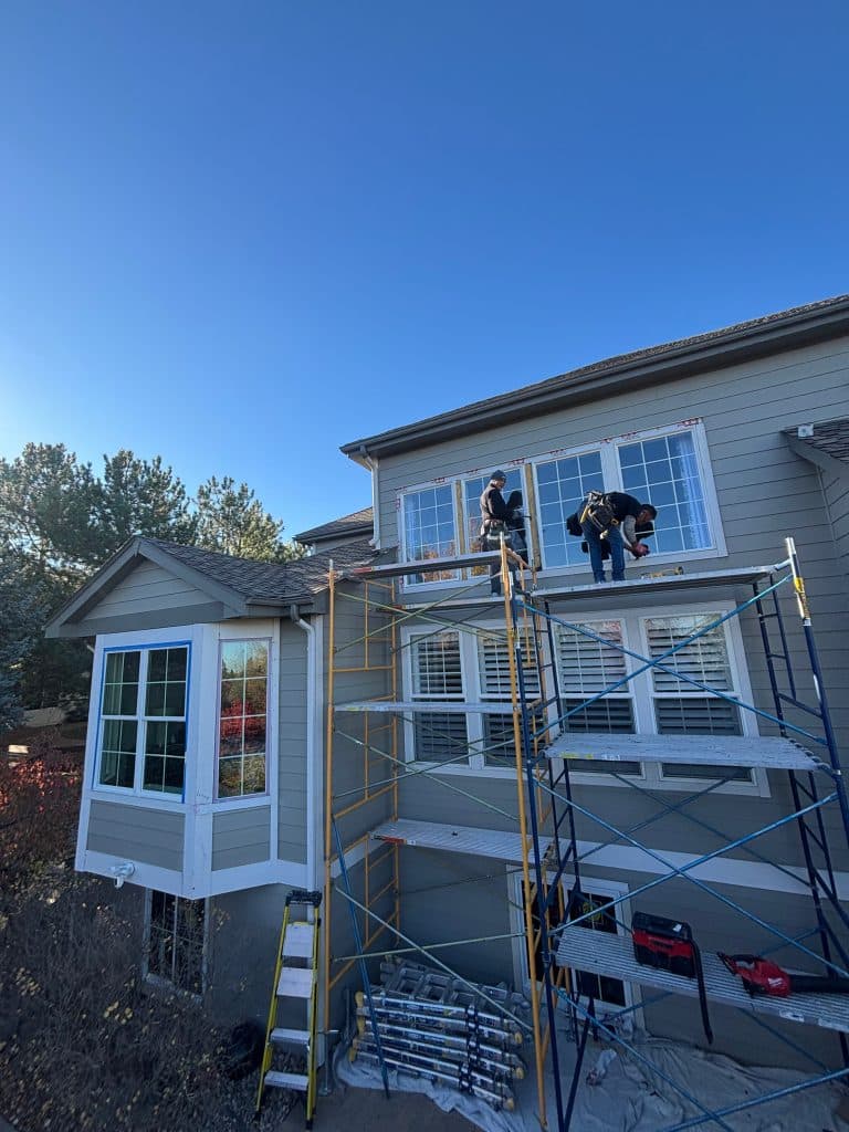 Crew on scaffolding installing replacement windows on a two-story Castle Rock, CO home